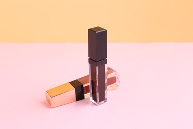 Photo of Two lip glosses on pink and orange background