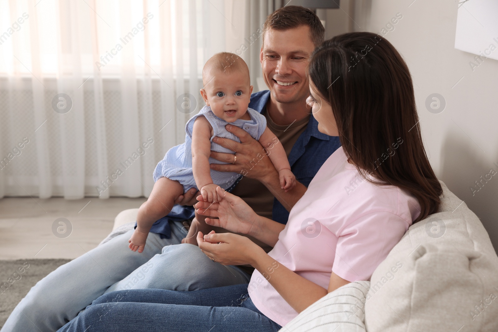 Photo of Happy family with their cute baby on sofa in living room