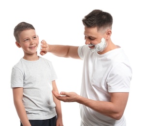 Photo of Dad applying shaving foam on son's face, white background
