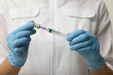 Photo of Doctor filling syringe with hepatitis vaccine from glass vial, closeup