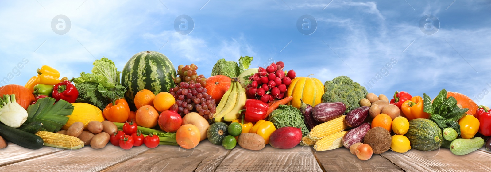 Image of Assortment of fresh organic fruits and vegetables on wooden table outdoors. Banner design