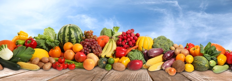 Assortment of fresh organic fruits and vegetables on wooden table outdoors. Banner design