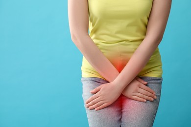 Image of Woman suffering from cystitis symptoms on light blue background, closeup