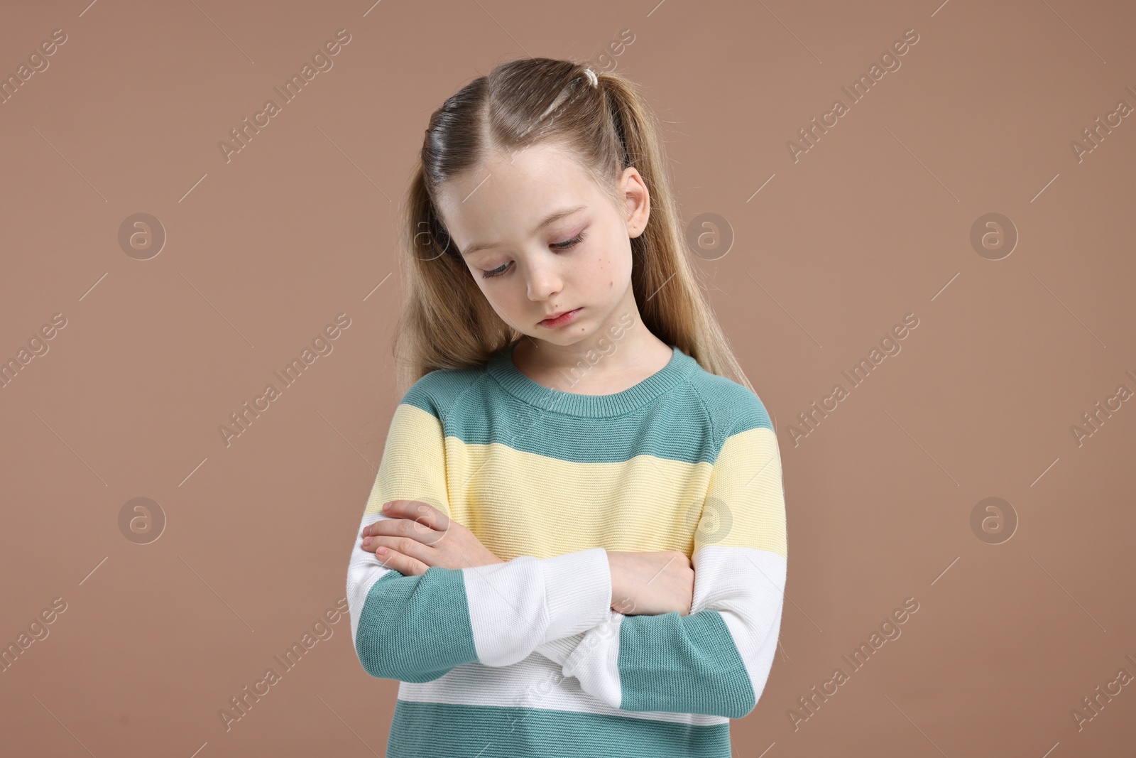 Photo of Portrait of sad girl with crossed arms on light brown background