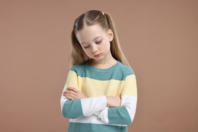 Photo of Portrait of sad girl with crossed arms on light brown background