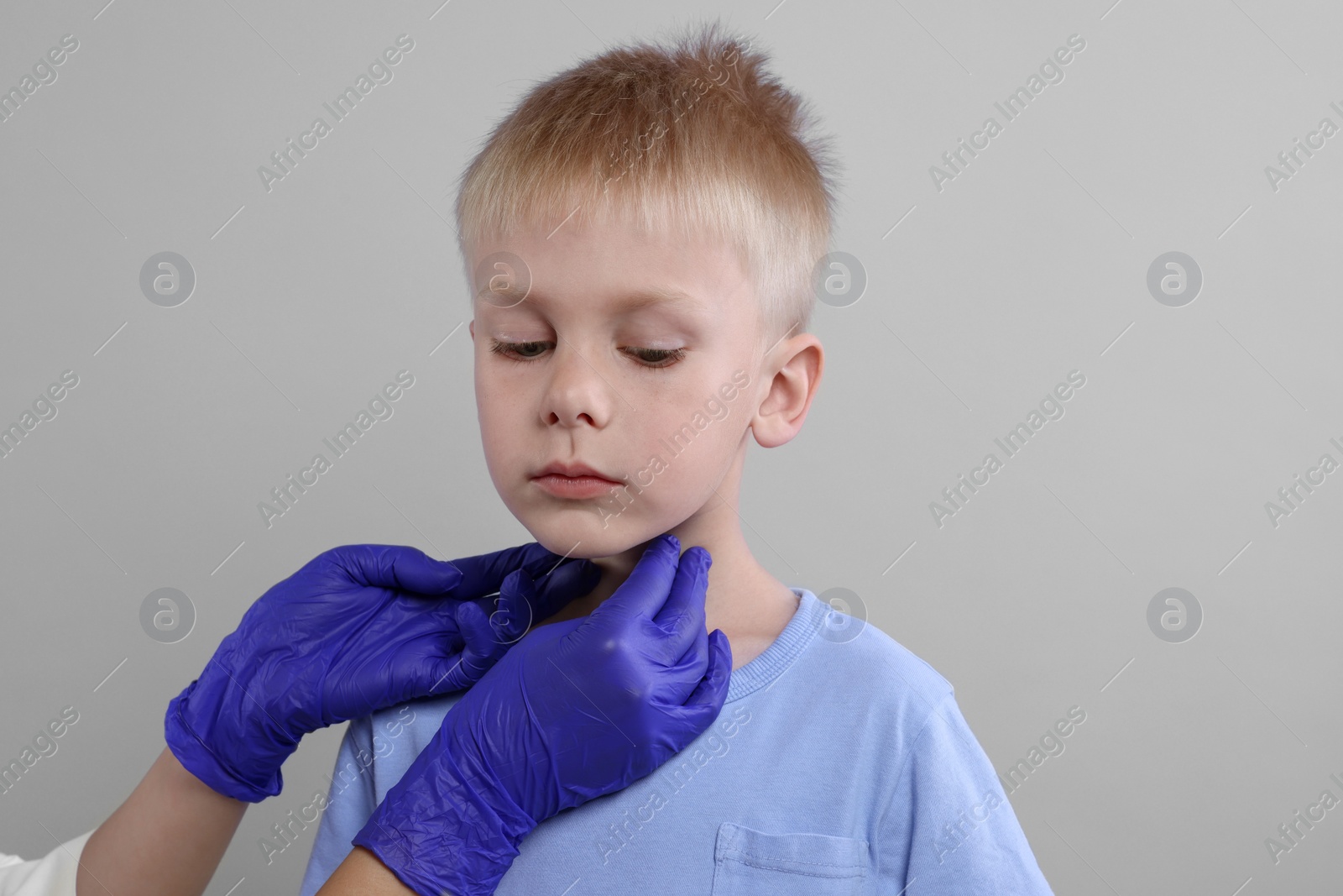 Photo of Endocrinologist examining boy's thyroid gland on light grey background, closeup