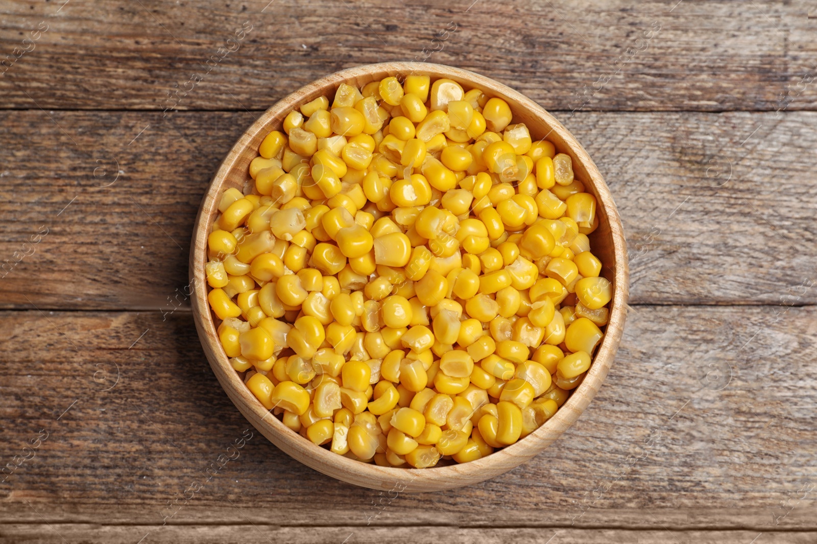 Photo of Delicious canned corn on wooden table, top view