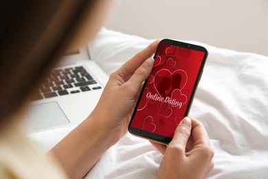 Image of Woman visiting dating site via smartphone indoors, closeup