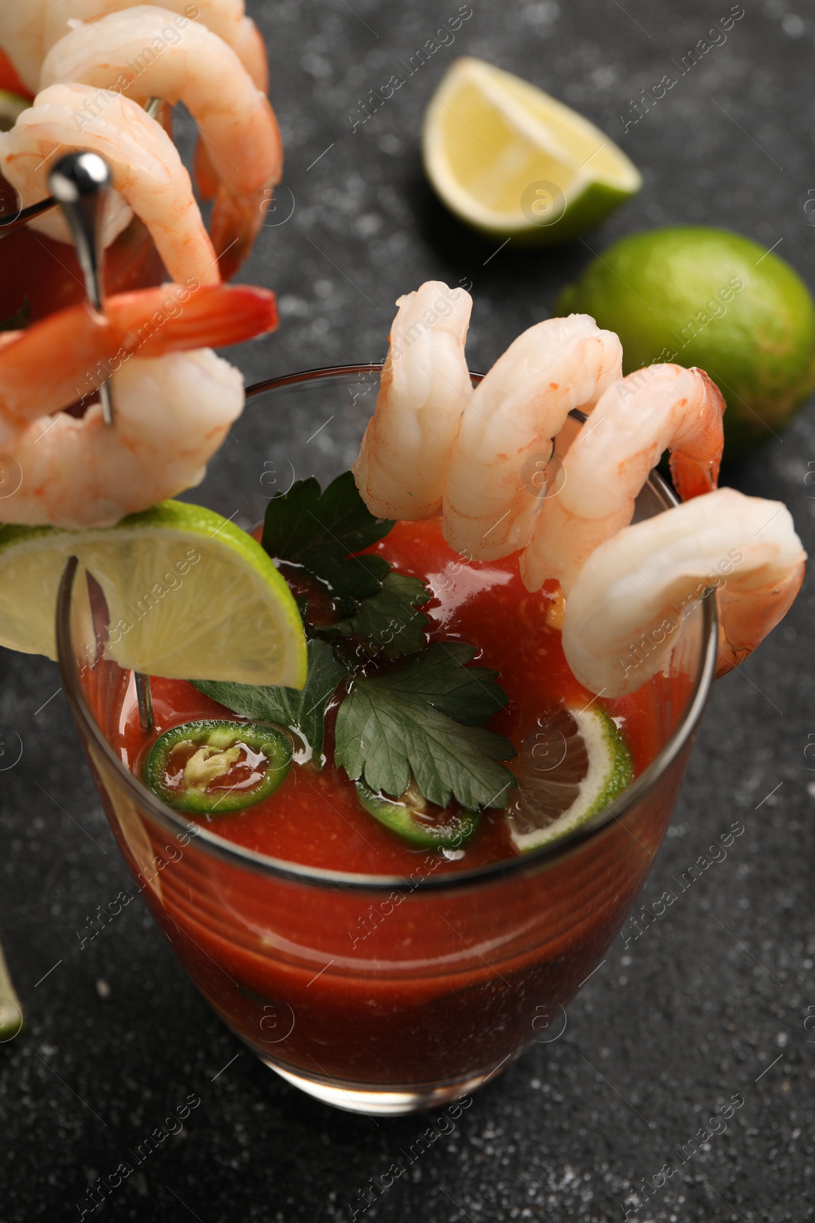 Photo of Tasty shrimp cocktail with sauce in glasses and limes on grey textured table, closeup