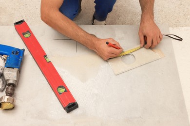 Photo of Worker making socket hole in tile indoors, closeup