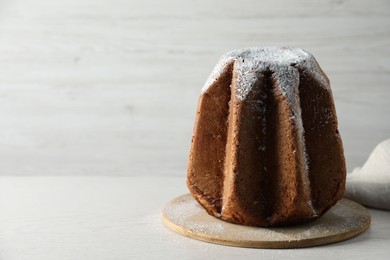Photo of Delicious Pandoro cake decorated with powdered sugar on white wooden table, space for text. Traditional Italian pastry