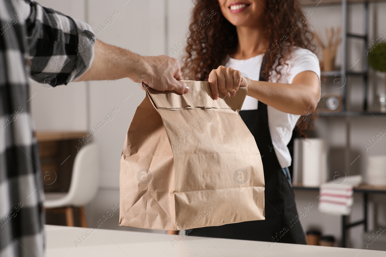 Photo of Worker giving paper bag to customer in cafe, closeup