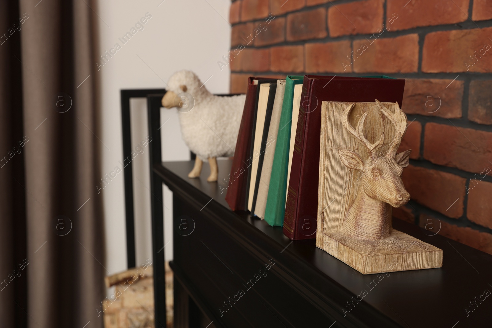 Photo of Bookends with books on fireplace near red brick wall indoors, space for text