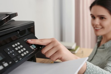 Woman using modern printer at workplace indoors, selective focus