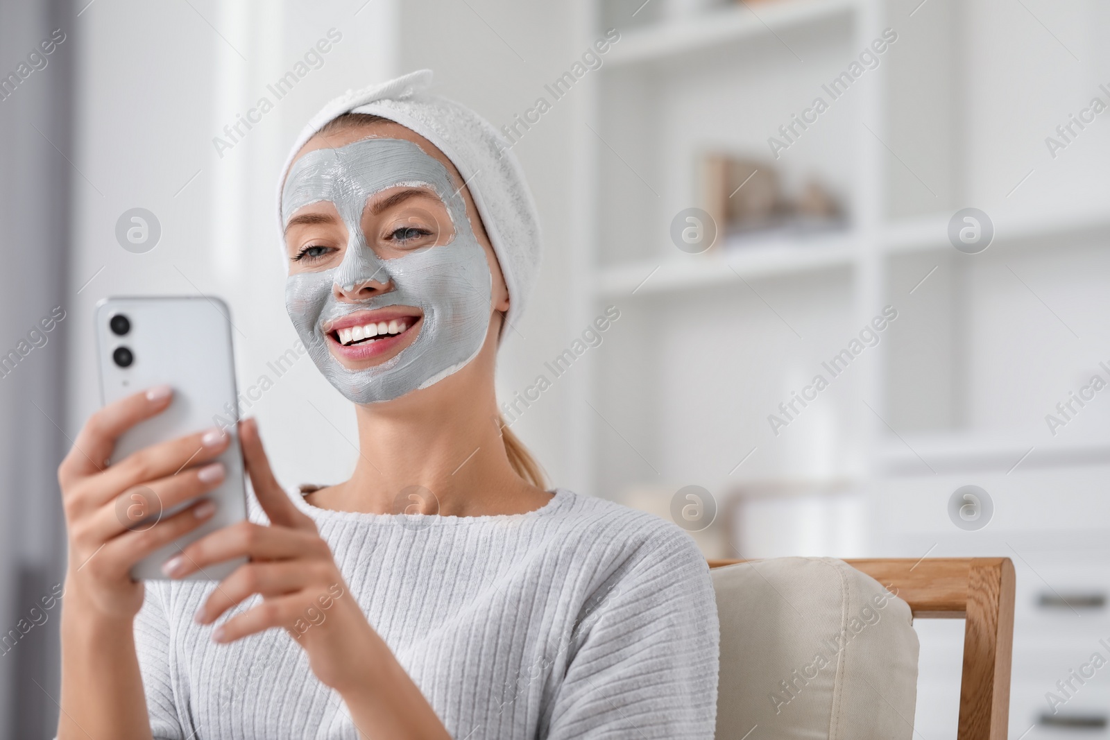 Photo of Young woman with face mask using smartphone at home, space for text. Spa treatments