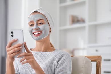 Photo of Young woman with face mask using smartphone at home, space for text. Spa treatments