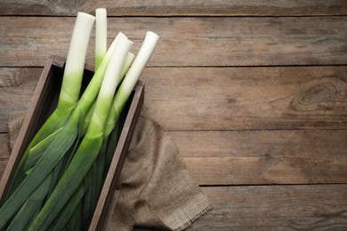 Photo of Fresh raw leeks on wooden table, top view. Space for text