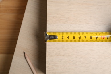 Photo of Tape measure and pencil on wooden surface, flat lay