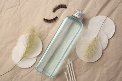 Flat lay composition with makeup remover and false eyelashes on crumpled paper