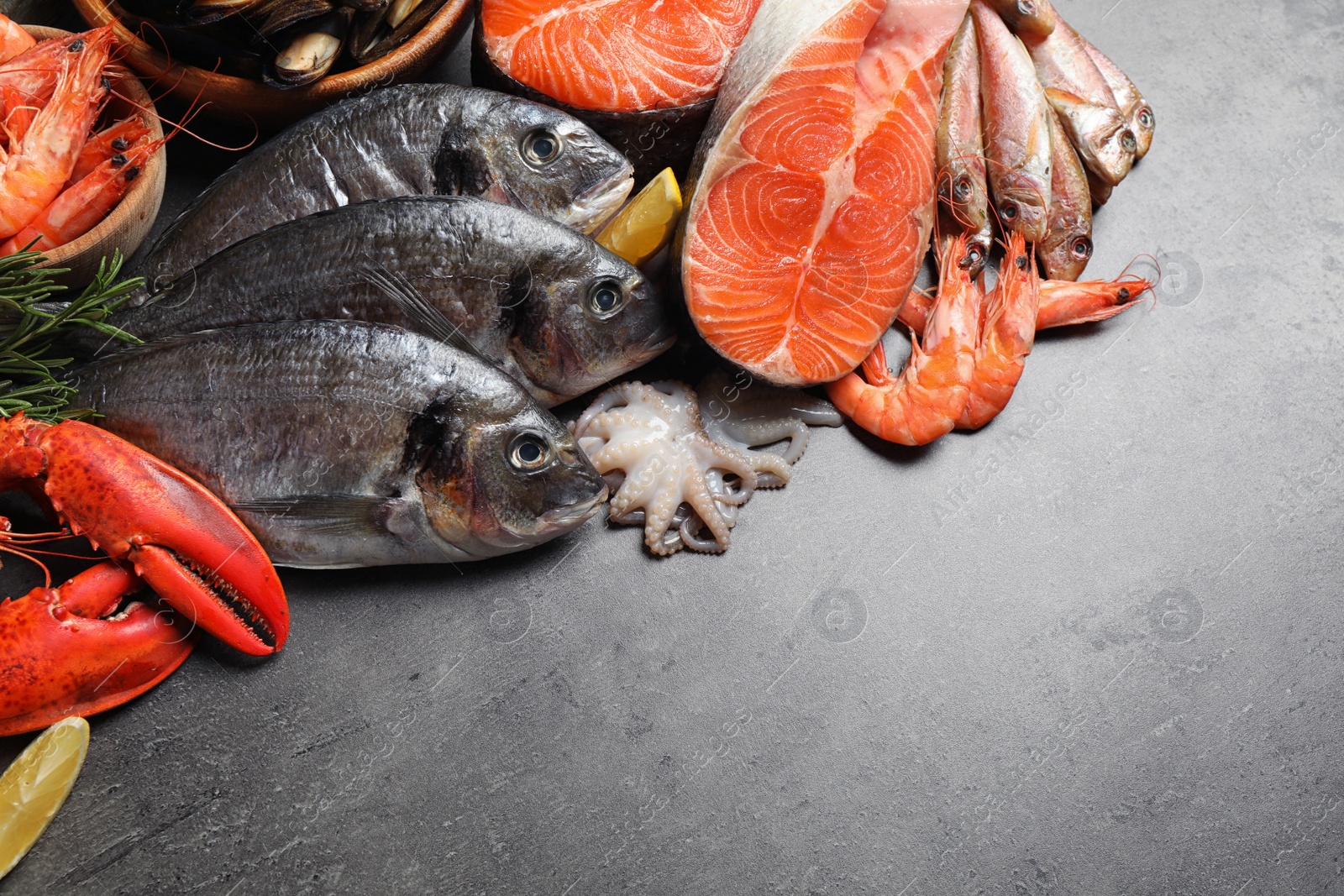 Photo of Fresh fish and different seafood on grey table, flat lay. Space for text