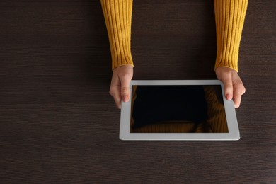 Photo of Woman working with tablet at wooden table, top view. Space for text