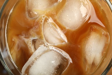 Photo of Coffee with milk and ice cubes in glass, top view