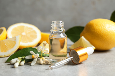 Photo of Citrus essential oil, flower and lemons on light table