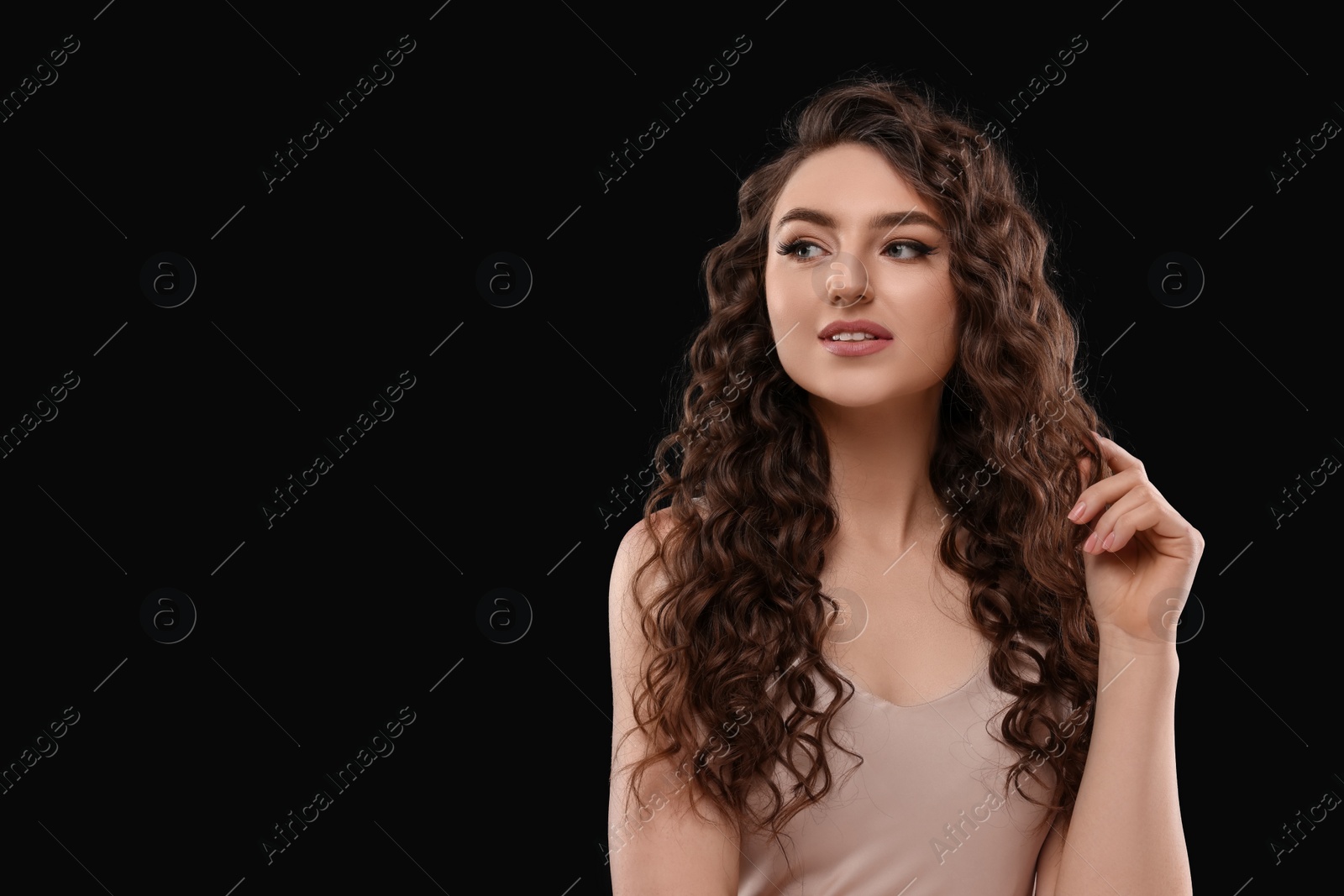 Photo of Beautiful young woman with long curly brown hair on black background, space for text