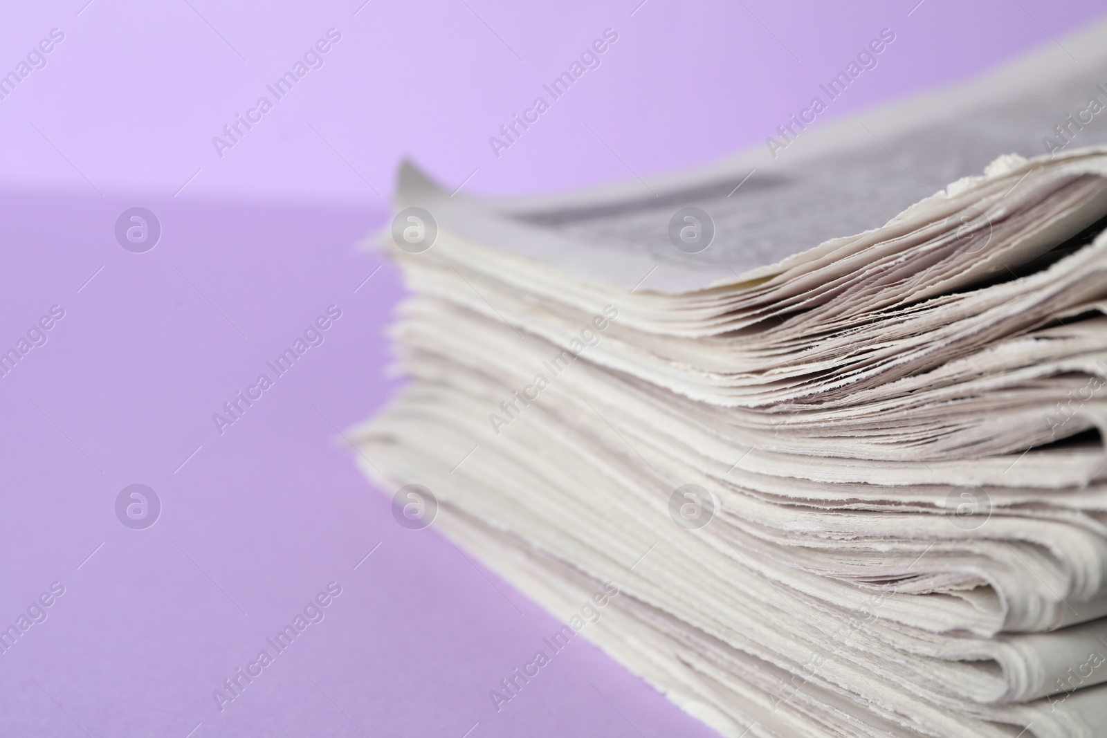 Photo of Stack of newspapers on light violet background, closeup. Journalist's work