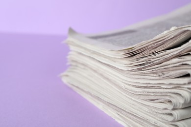 Photo of Stack of newspapers on light violet background, closeup. Journalist's work