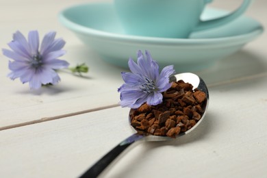 Spoon of chicory granules with flower on white wooden table, closeup