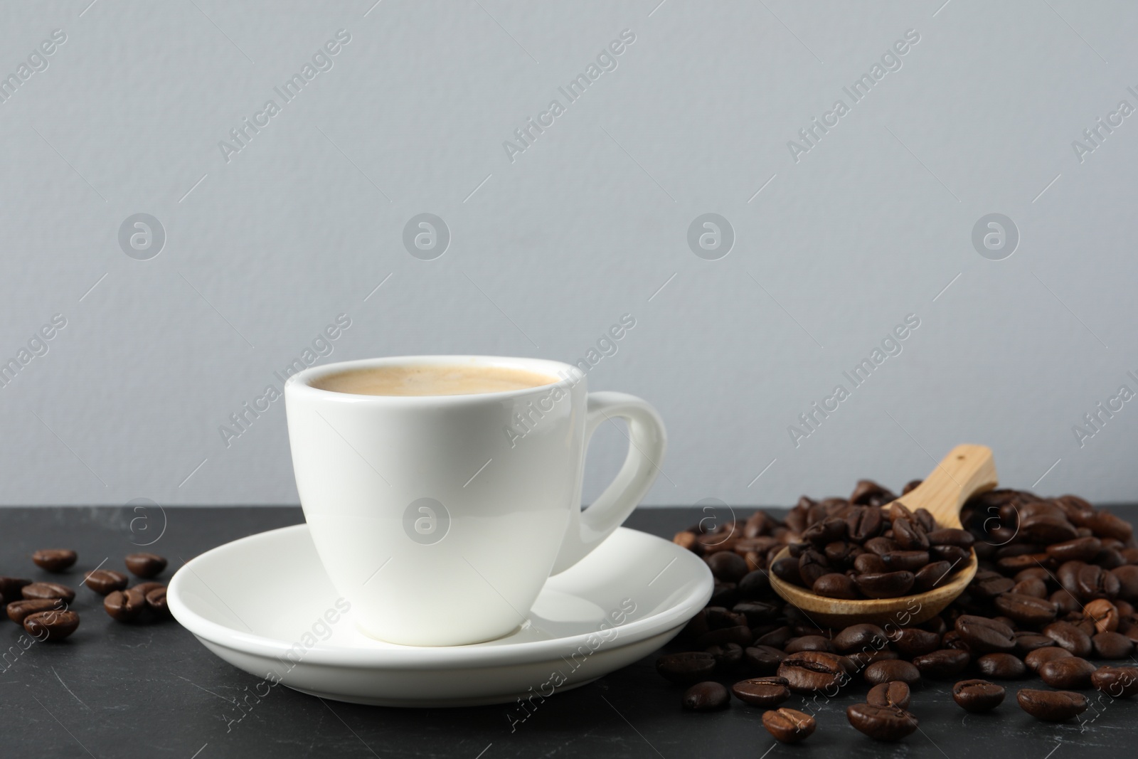 Photo of Cup of aromatic coffee and beans on grey table