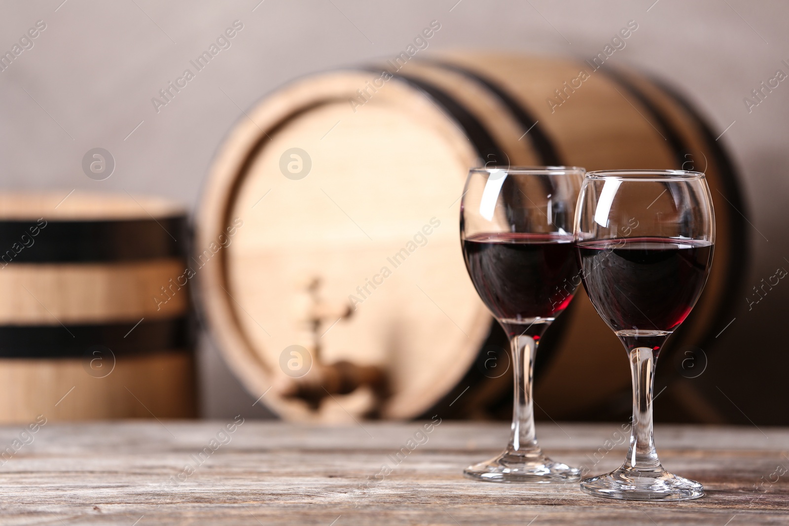 Photo of Glasses with red wine and blurred barrel on background