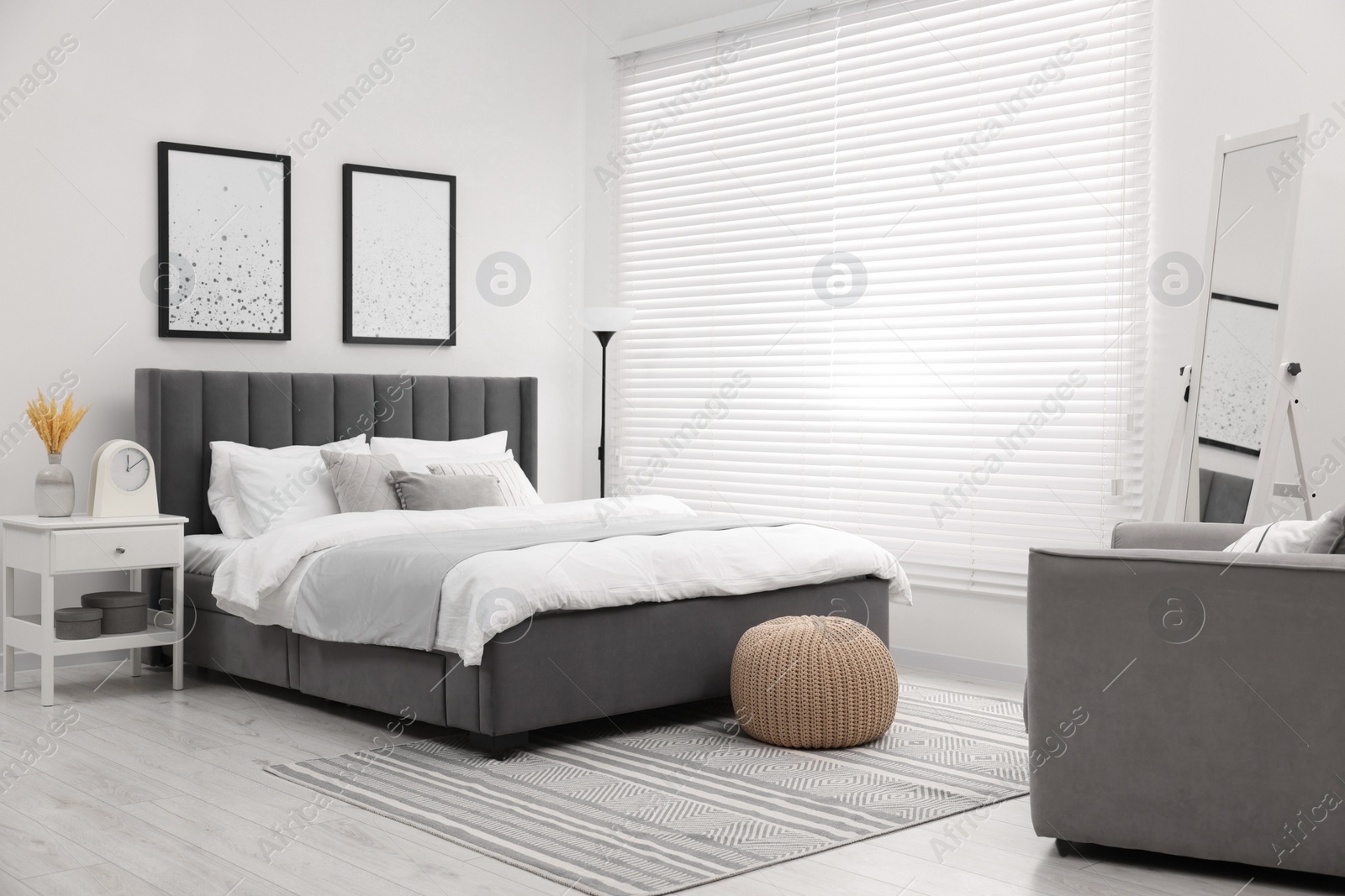 Photo of Stylish bedroom interior with large bed, bedside table and lamp