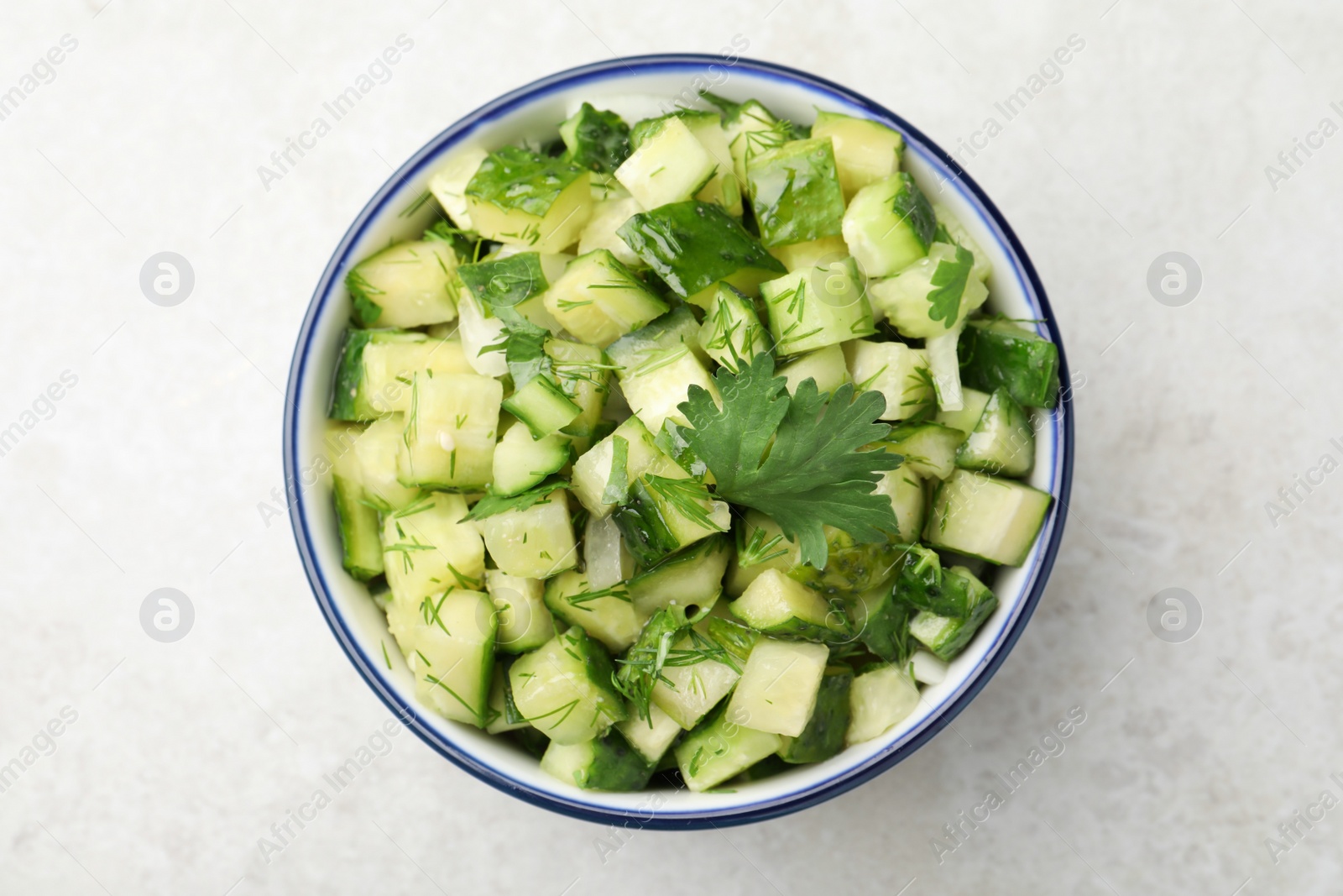 Photo of Bowl of delicious cucumber salad on light table, top view