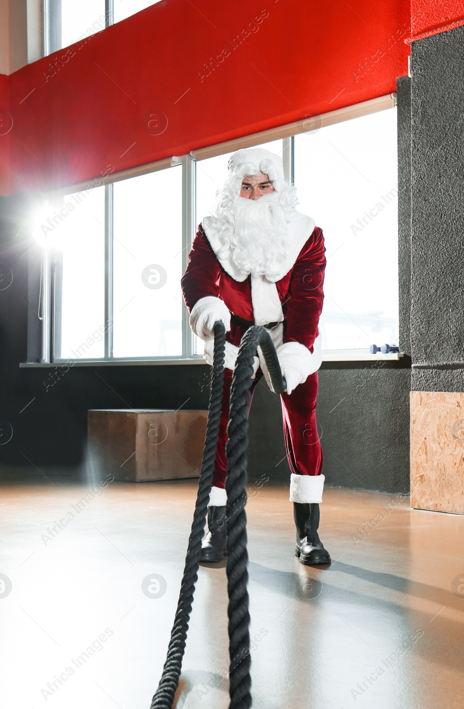 Photo of Young Santa Claus training with ropes in modern gym