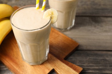 Photo of Glass with banana smoothie on wooden table, closeup. Space for text