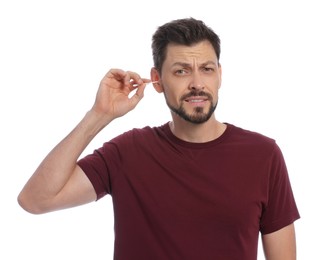 Photo of Emotional man cleaning ears on white background