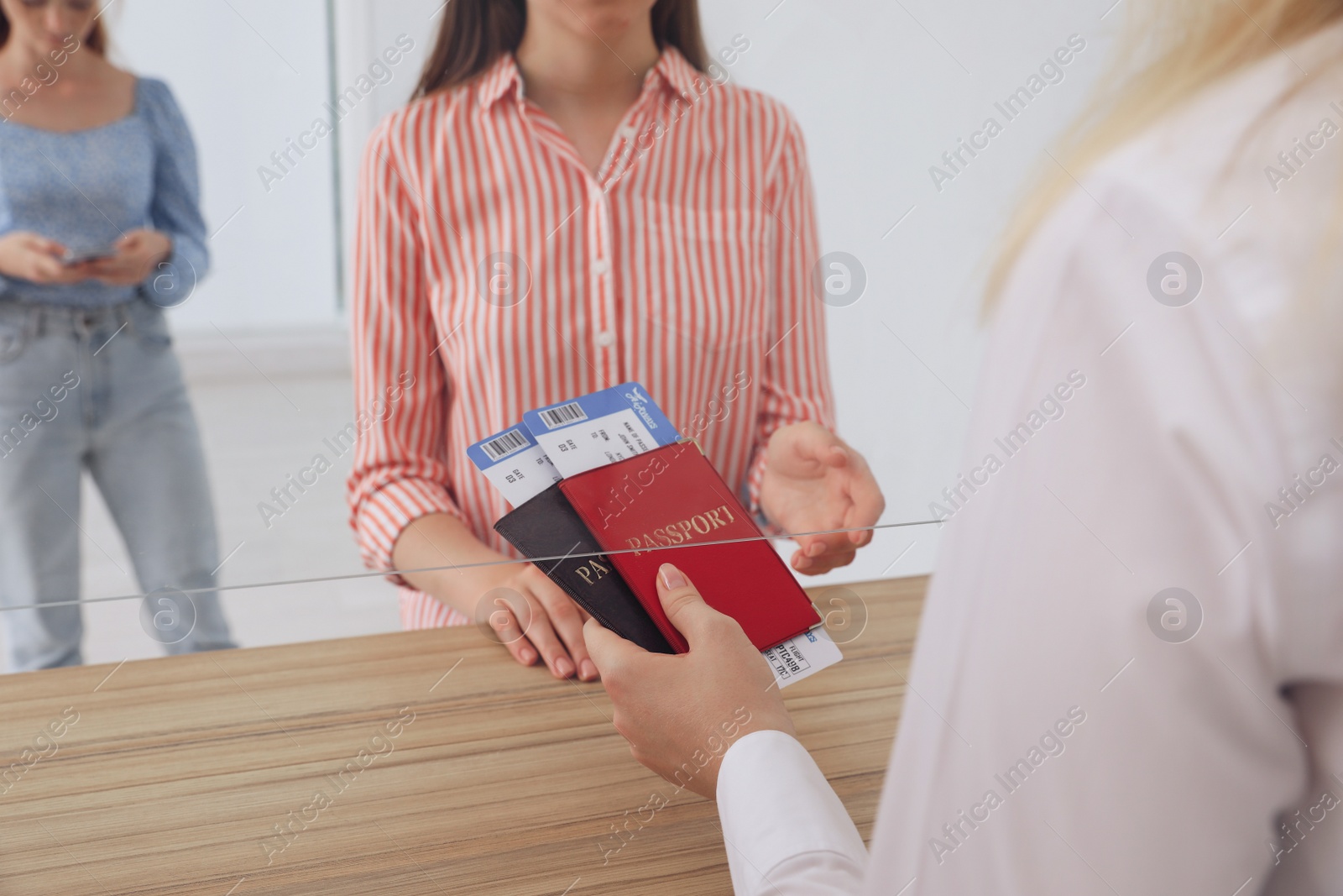 Photo of Agent giving passports with tickets to client at check-in desk in airport, closeup