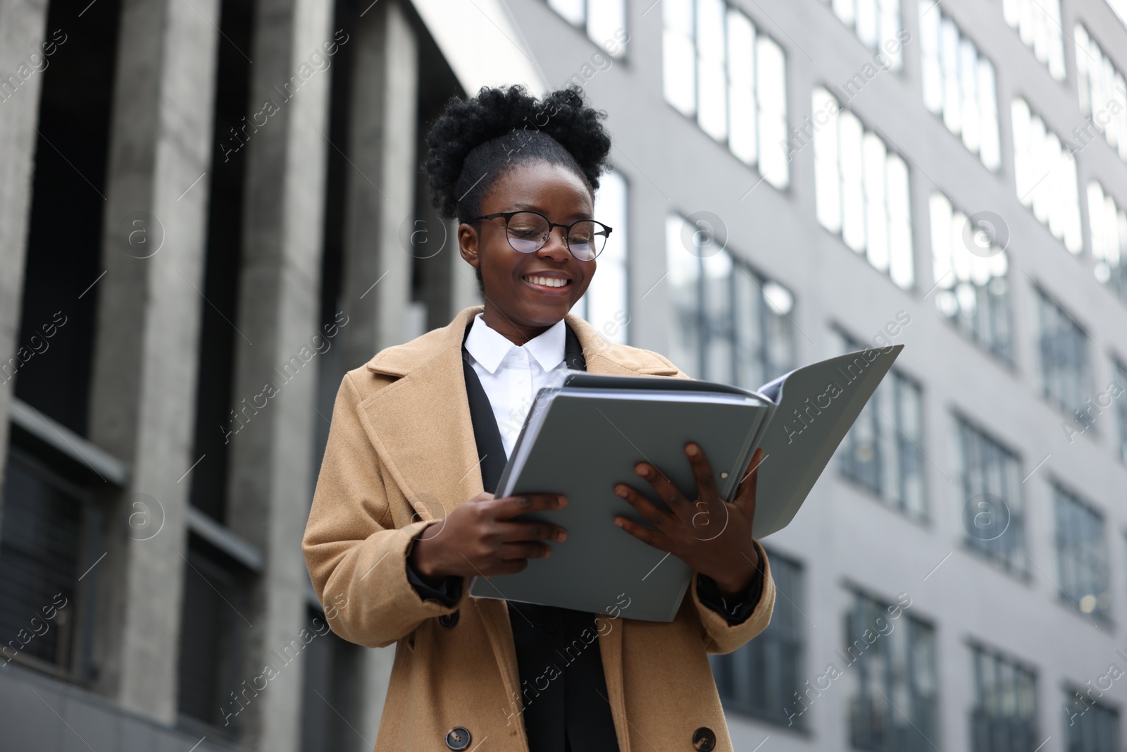 Photo of Happy woman with folders outdoors, low angle view. Lawyer, businesswoman, accountant or manager