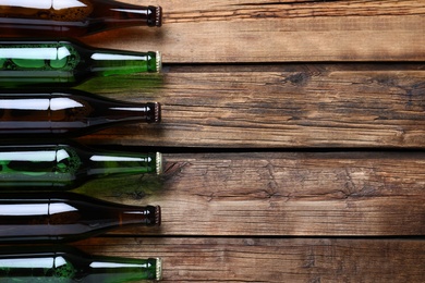 Bottles of beer on wooden table, flat lay. Space for text