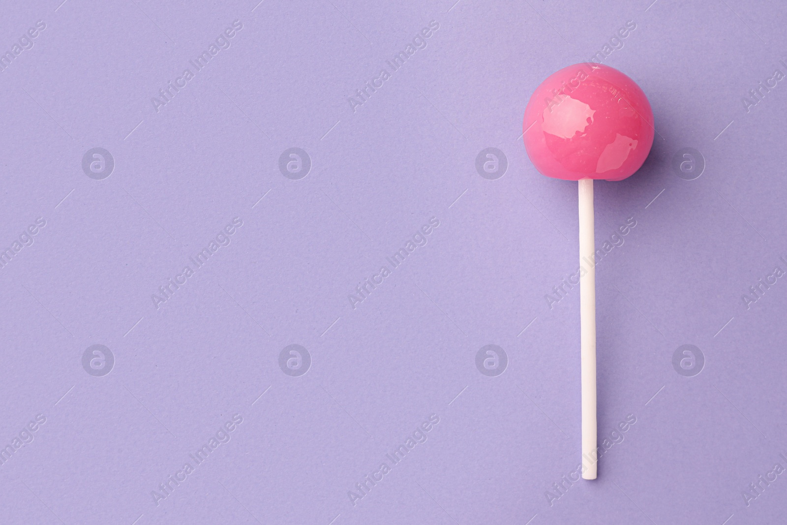 Photo of Tasty lollipop on violet background, top view. Space for text