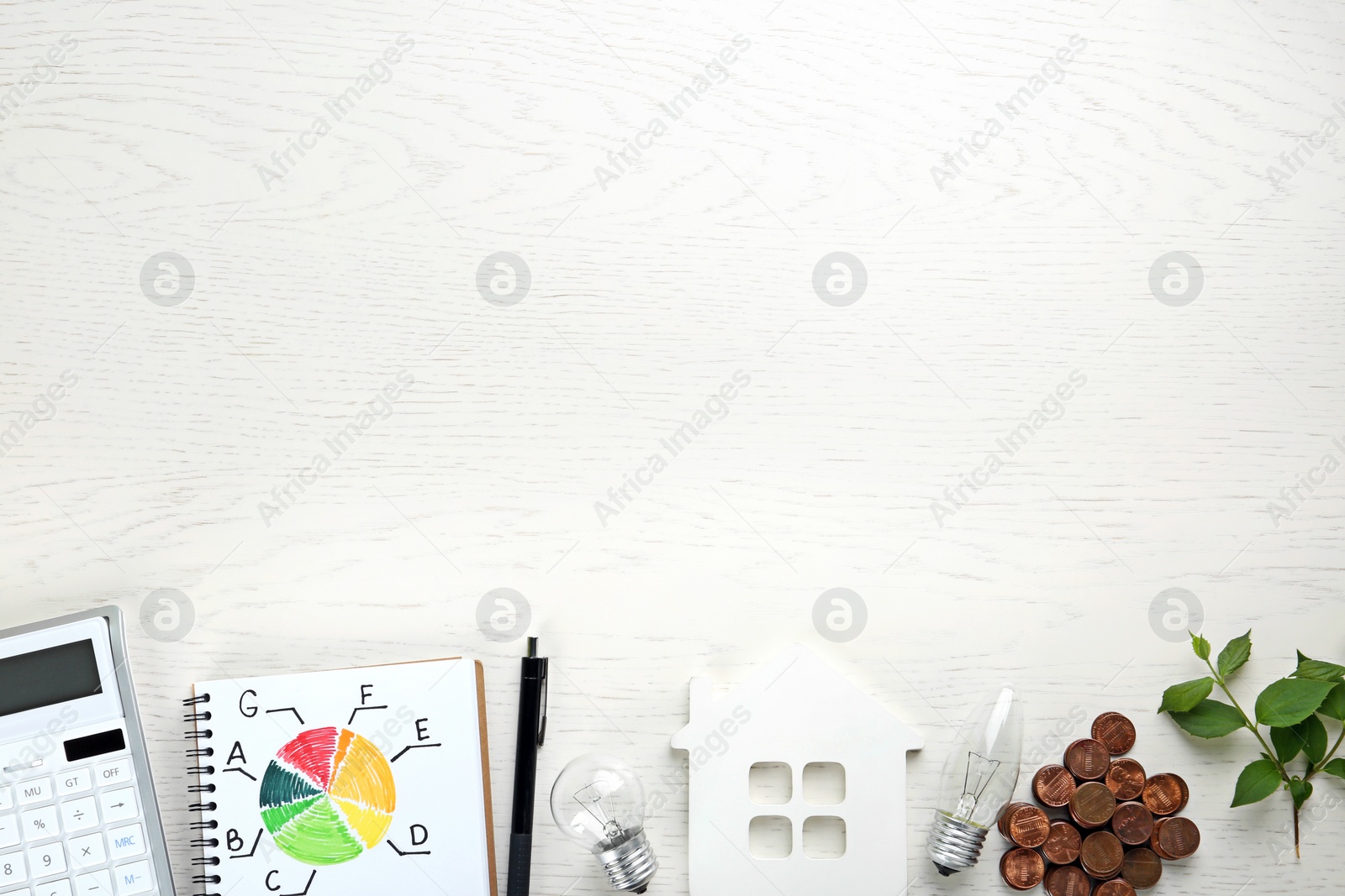 Photo of Flat lay composition with energy efficiency rating chart, house figure and coins on white wooden background. Space for text