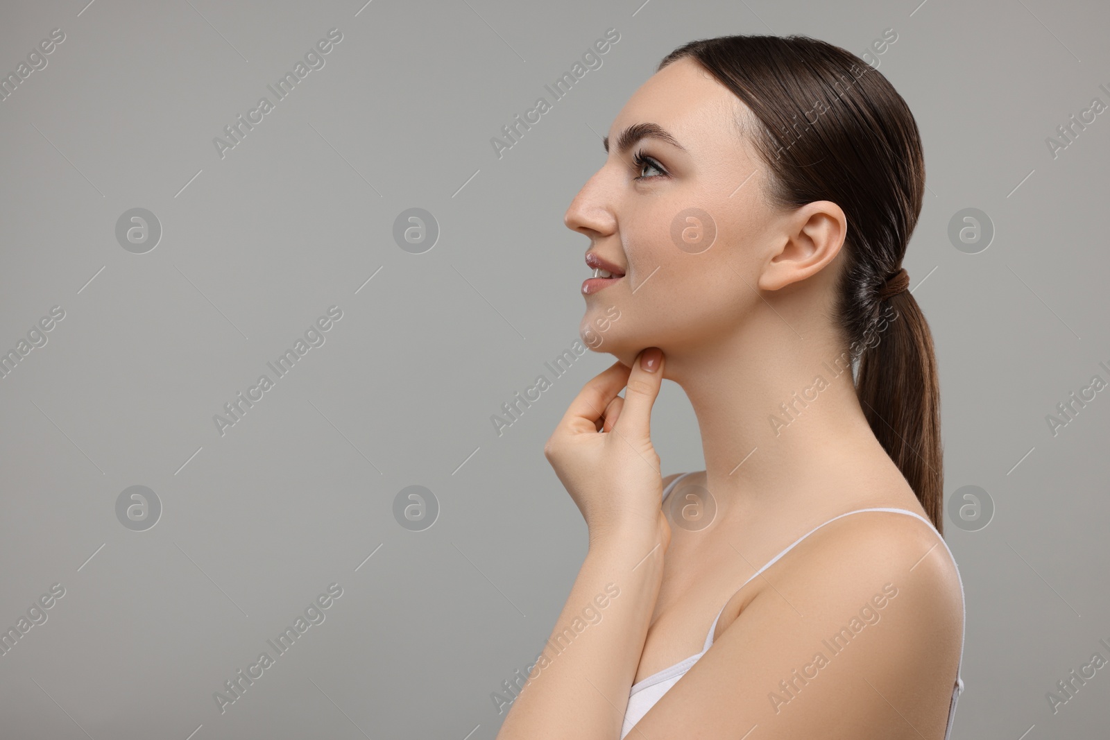 Photo of Beautiful woman touching her chin on grey background. Space for text