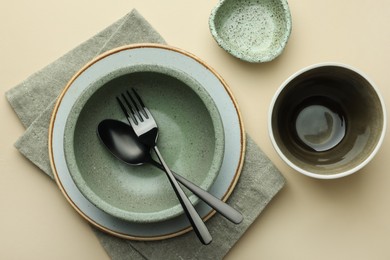 Stylish empty dishware and cutlery on beige background, flat lay