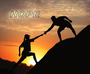 Image of Concept of hope. Man helping woman to climb on hill at sunset
