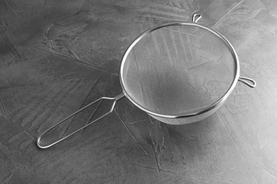 Photo of One metal sieve on grey table. Cooking utensil