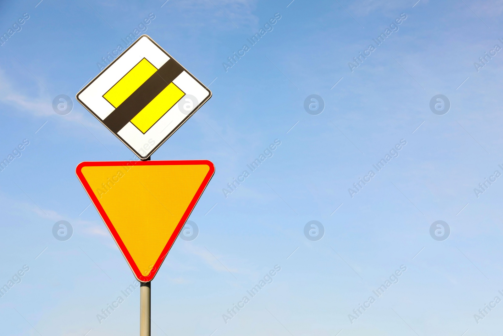 Photo of Traffic signs End Of Priority Road and Yield outdoors on sunny day, closeup. Space for text