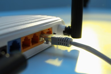 Photo of Connected cable to router on white table, closeup. Wireless internet communication