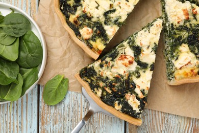 Photo of Taking piece of delicious homemade spinach quiche on rustic wooden table, flat lay